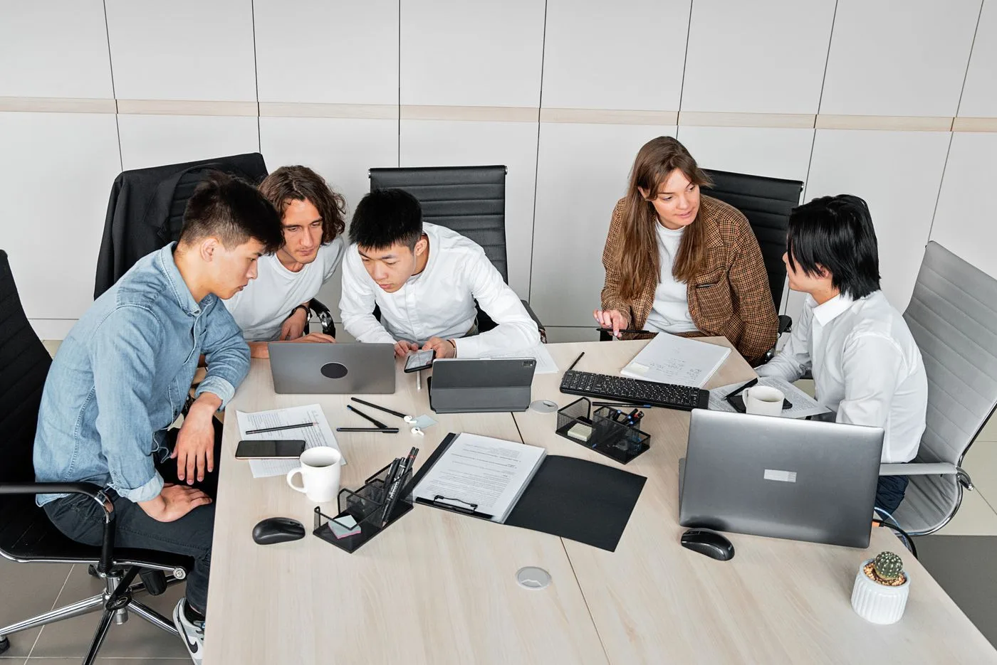 A diverse group of colleagues working together in an office setting with laptops and documents
