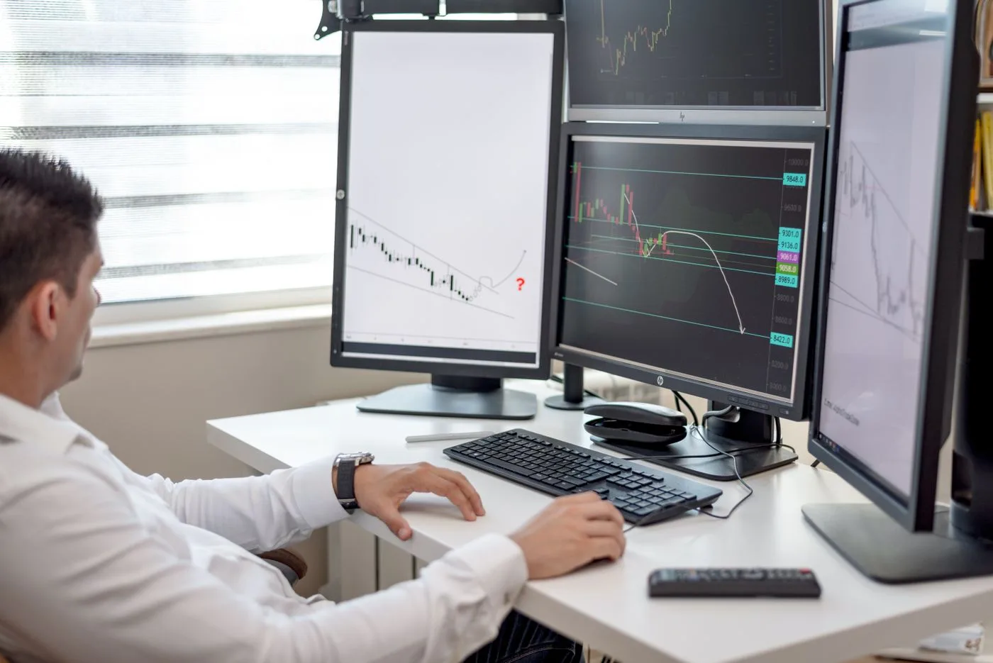 A professional at his desk monitoring data on multiple screens