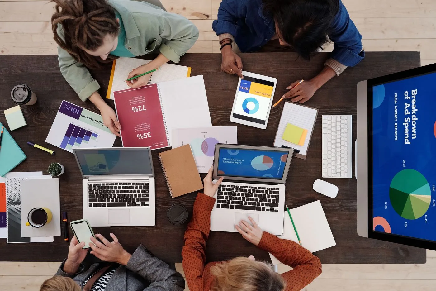 A diverse team collaborating on digital marketing strategies at a desk, using laptops and tablets