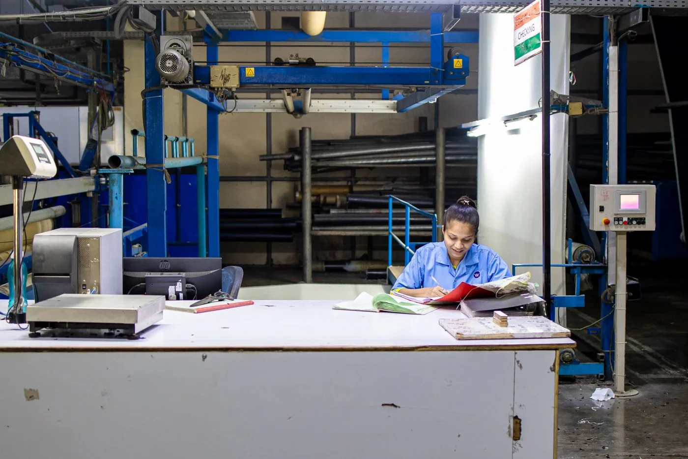Female worker in a textile factory analyzing production documents at a desk