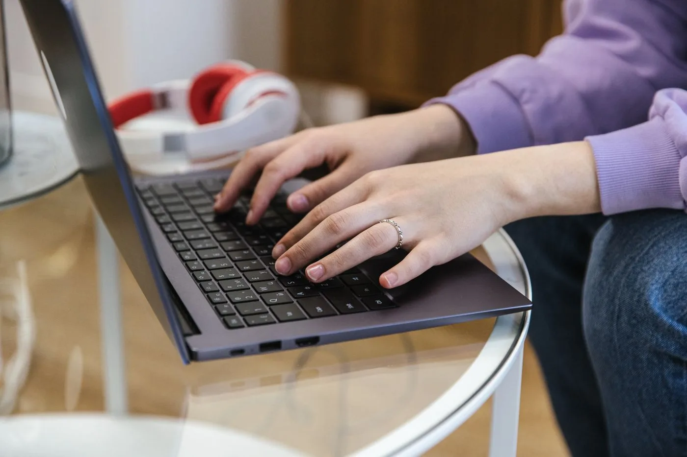 Close-up view of hands typing on a laptop indoors