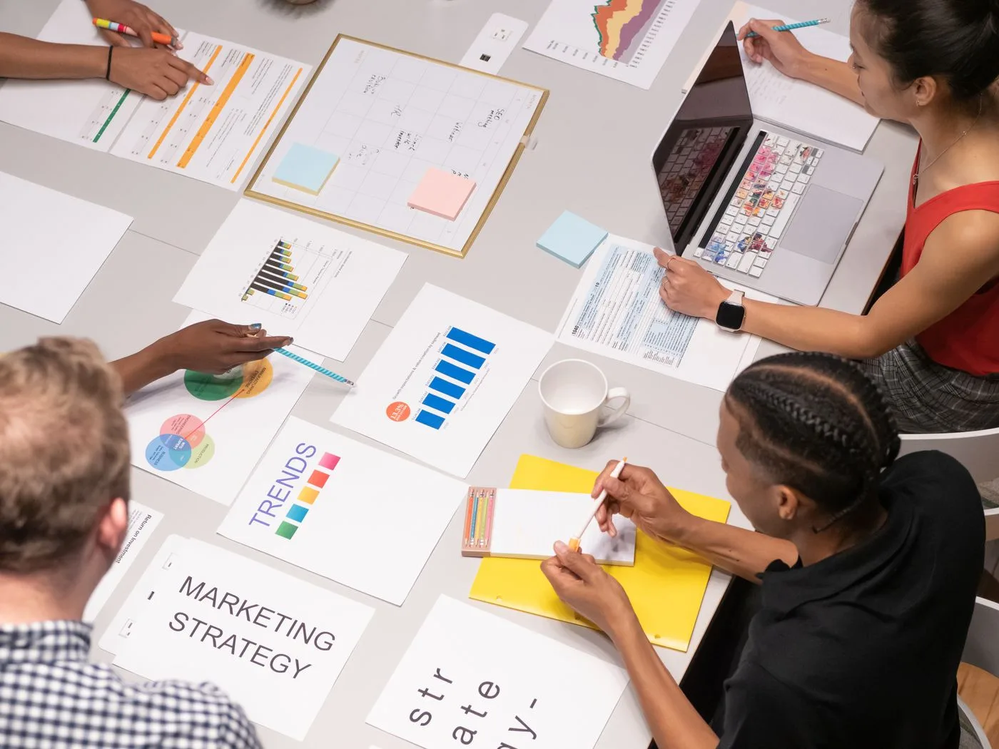 Overhead shot of diverse team analyzing marketing strategies with charts and graphs
