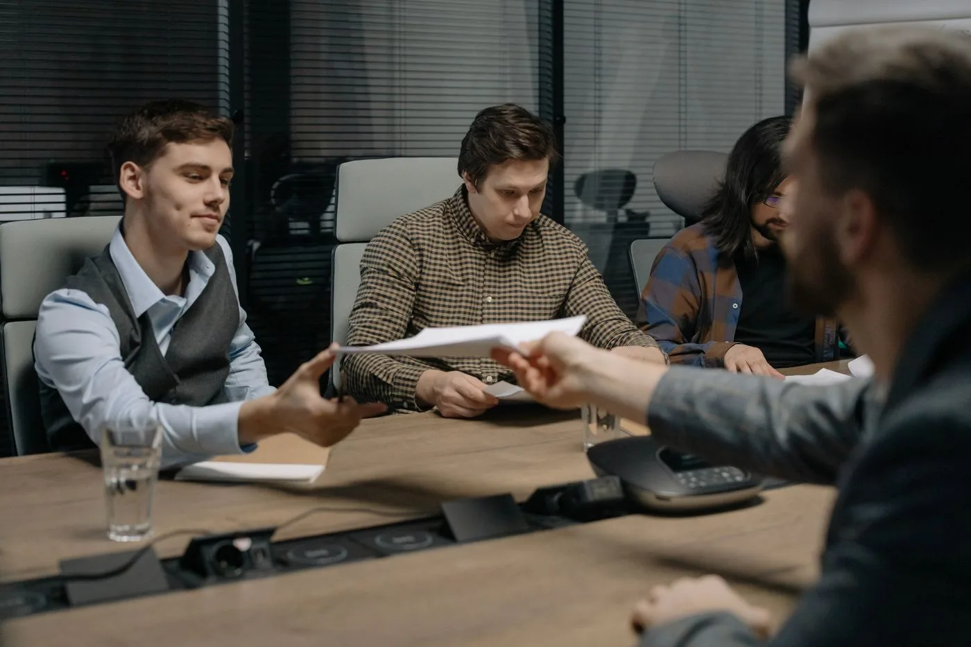 Four professionals exchanging documents during a meeting in an office setting