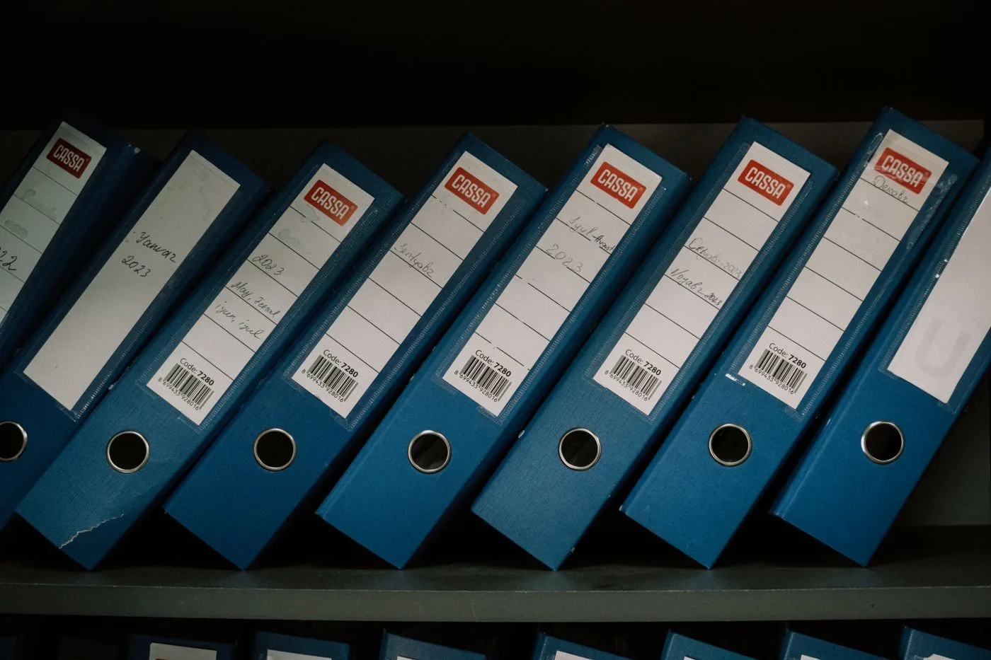 Neatly arranged blue office binders labeled with dates and names for organized storage