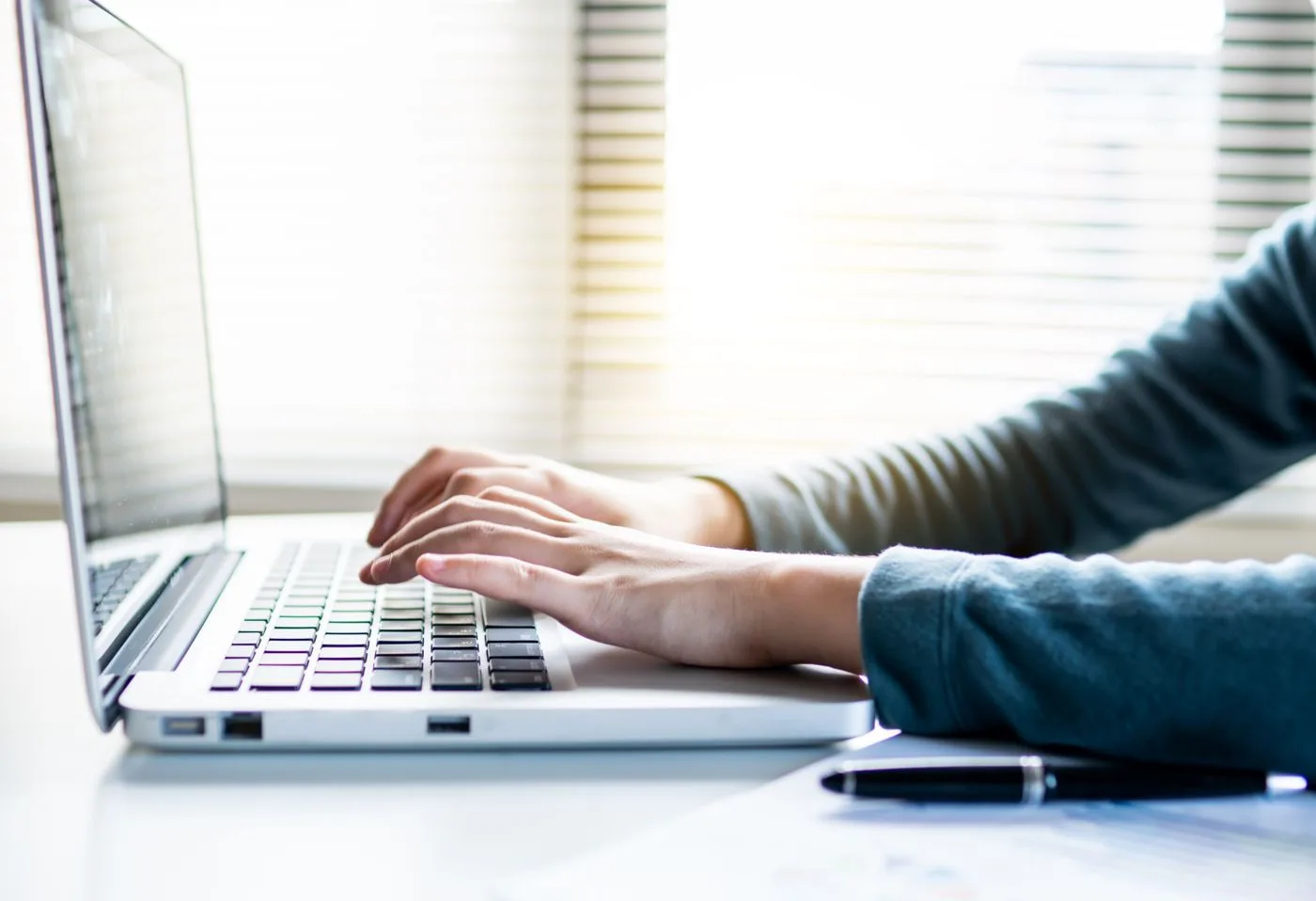 Close-up shot of hands typing on a laptop keyboard