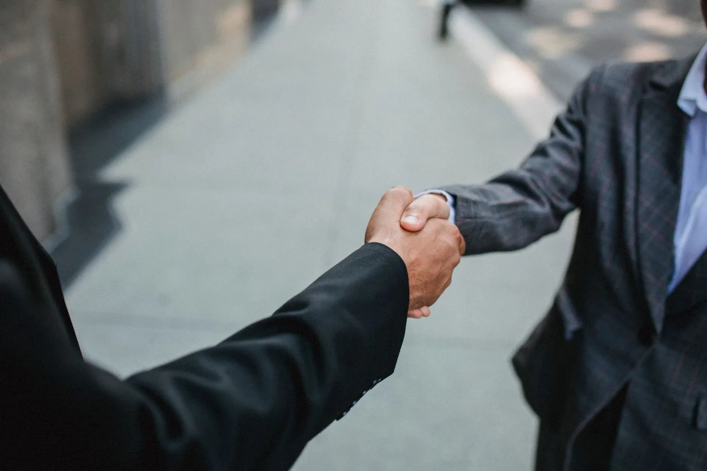 Close-up of two businessmen shaking hands outside