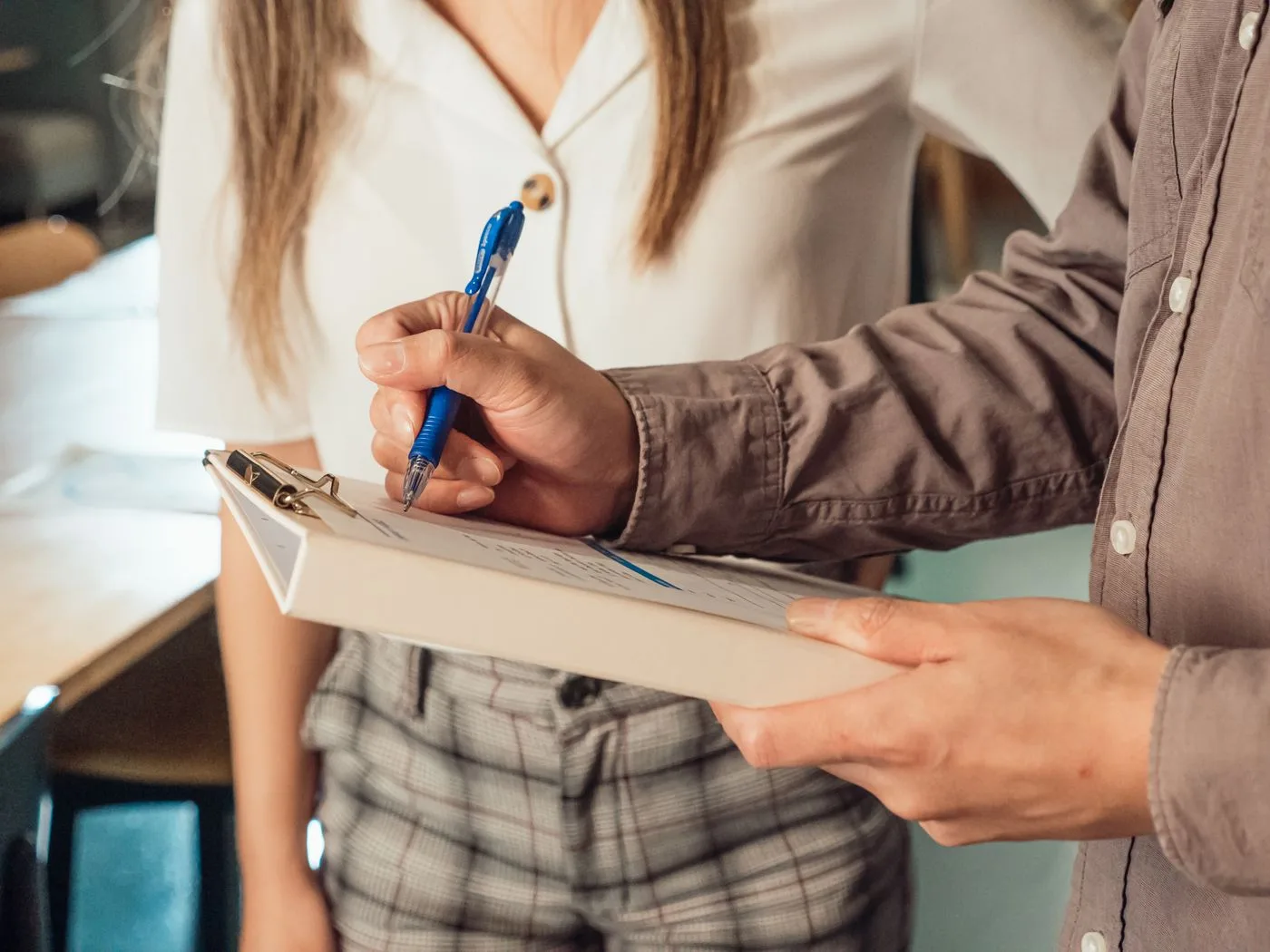 A person writing on a clipboard with a ballpen in an office setting