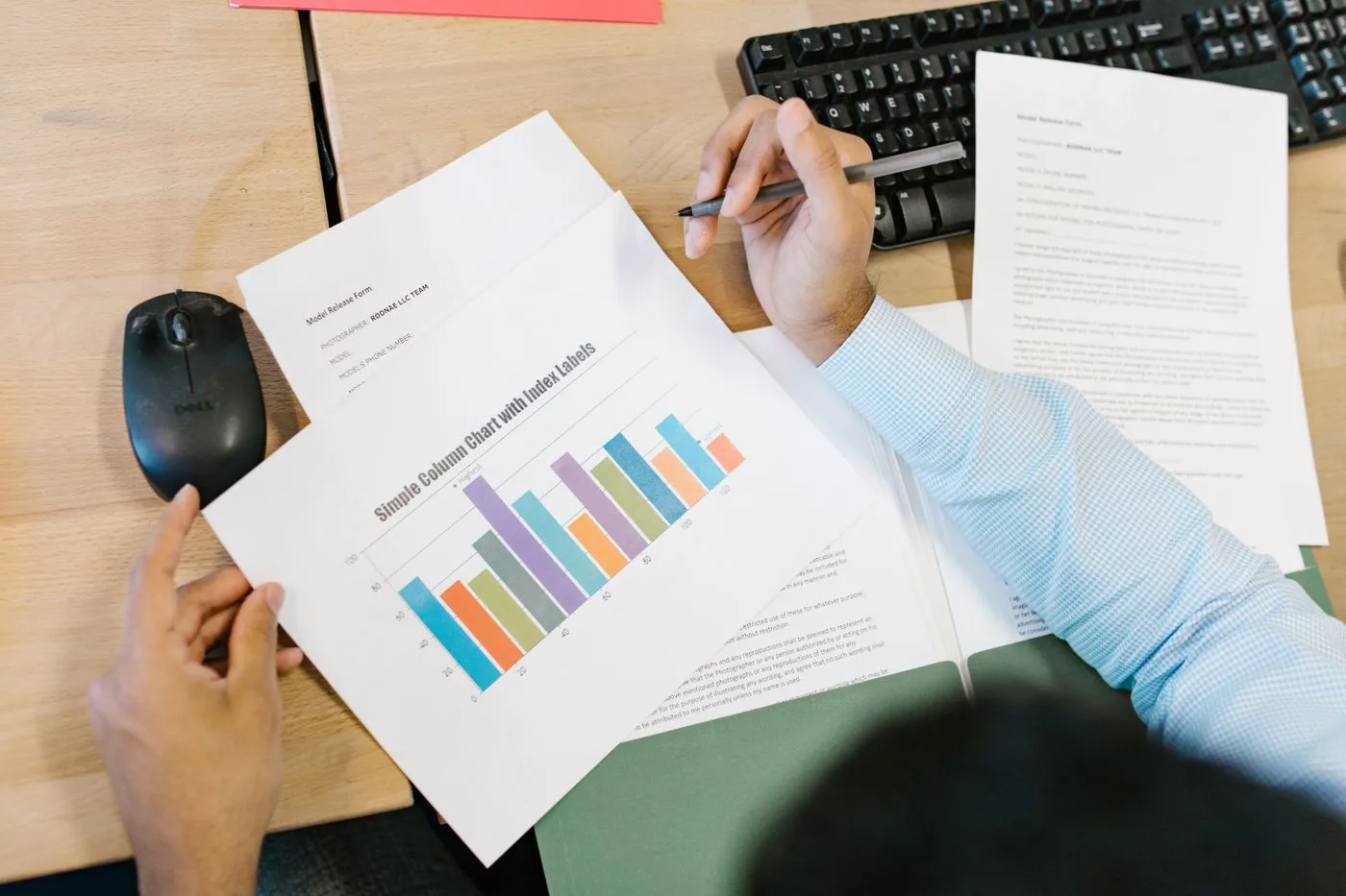 A business analyst reviews a colorful bar chart and documents at a desk, indicating data analysis