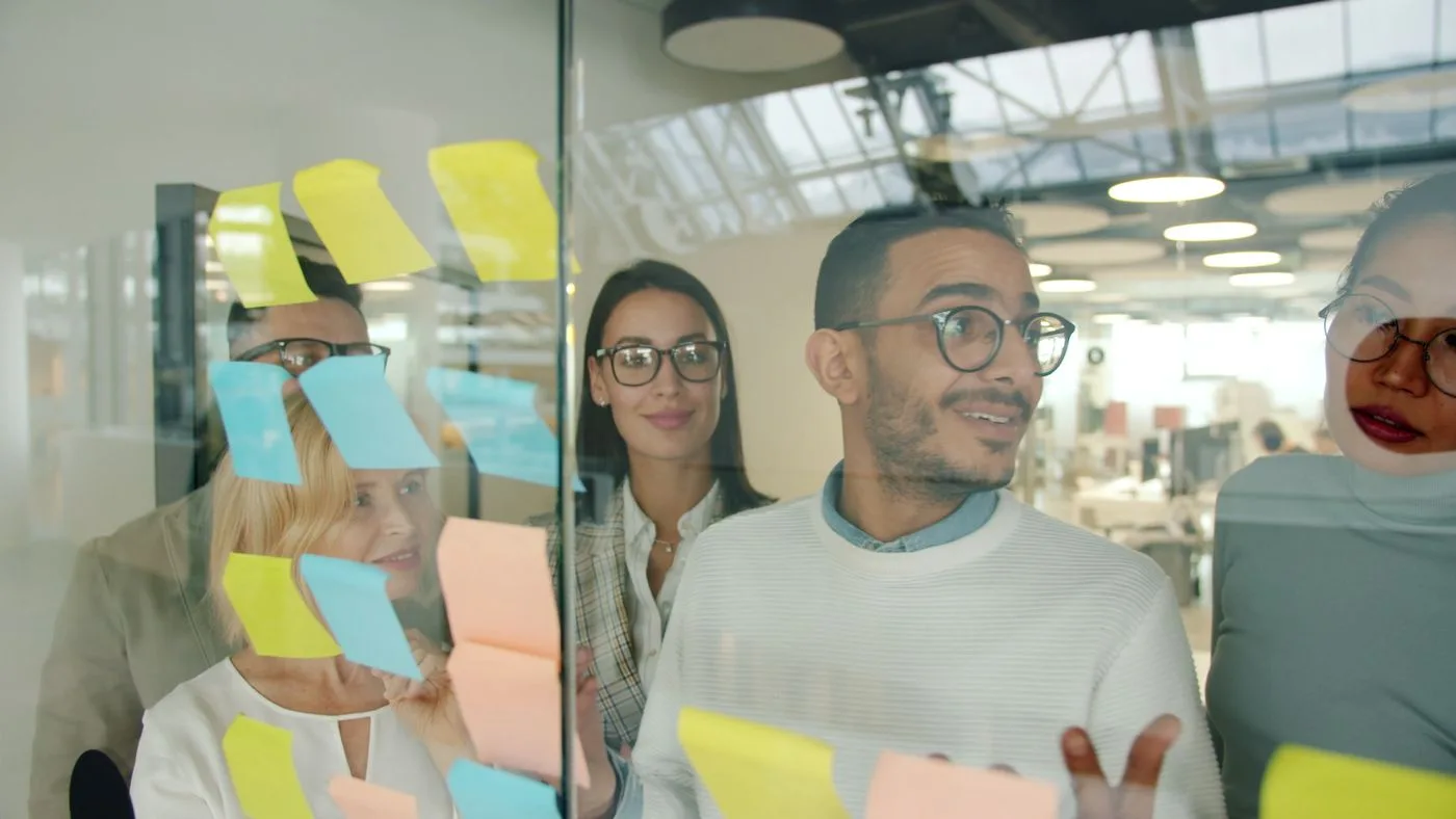 A diverse team collaborating in a modern office using colorful sticky notes