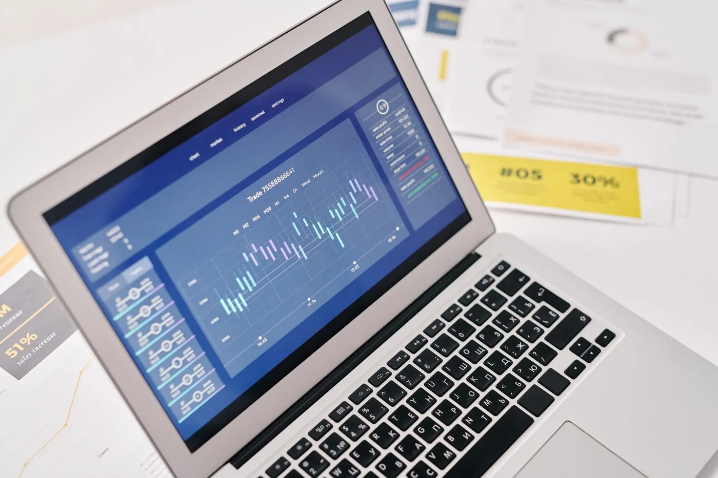 Open laptop displaying financial graphs and analytics with documents nearby