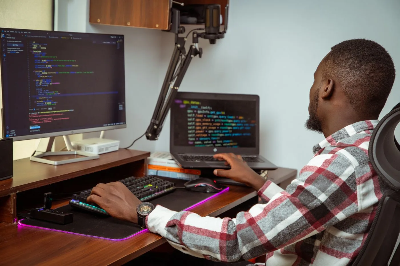 An African man coding on a desktop and laptop in a Nairobi office setting