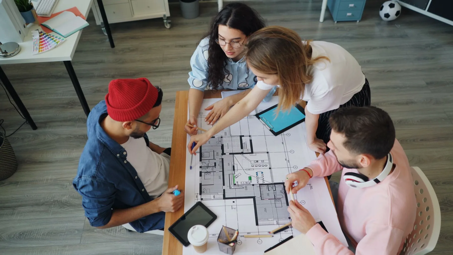 Creative team reviewing design layouts together at a desk with a color swatch deck, evaluating branding tool categories.