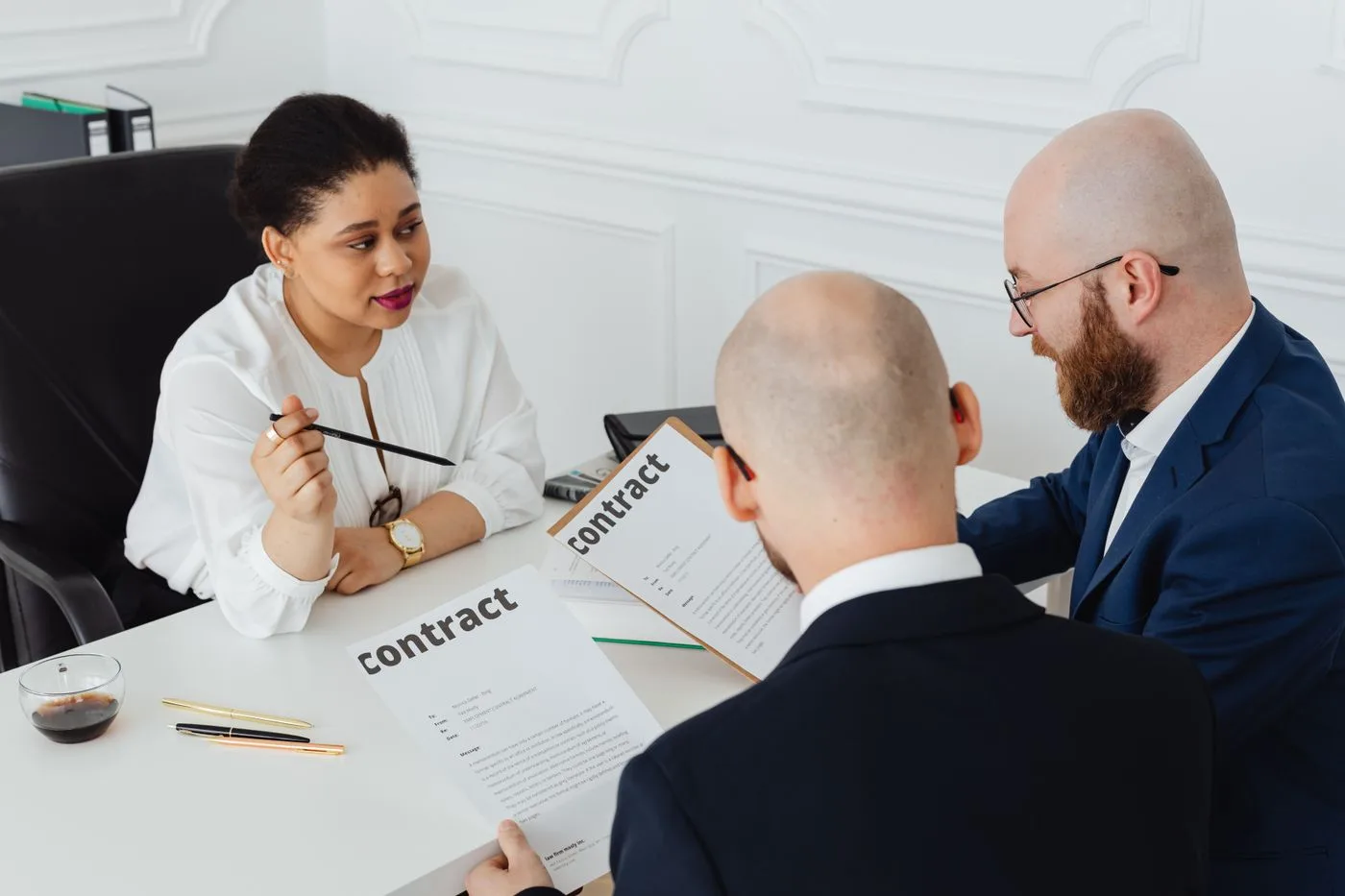 Three business professionals in discussion over a contract in a modern office setting