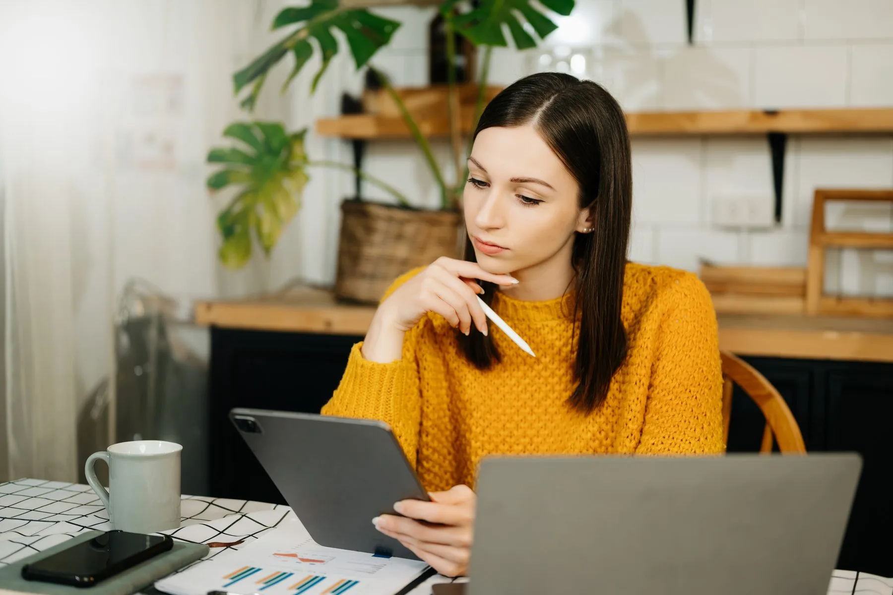Woman working on tablet and laptop at home