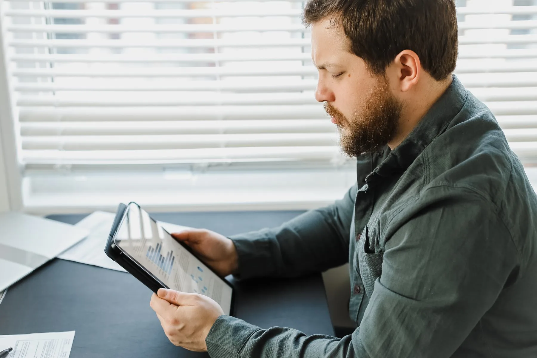 Bearded man analyzing charts on a tablet