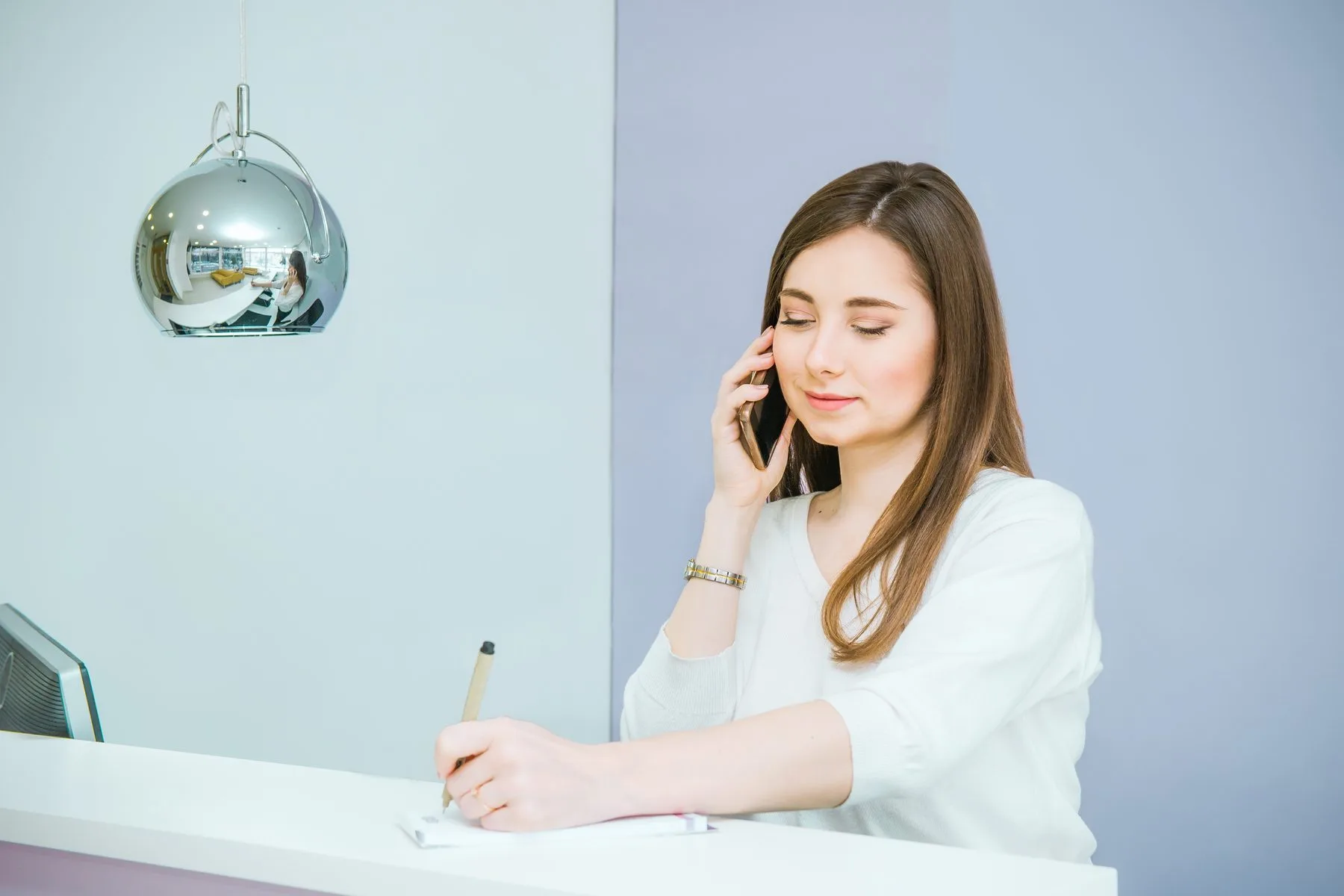 Woman taking notes while speaking on phone
