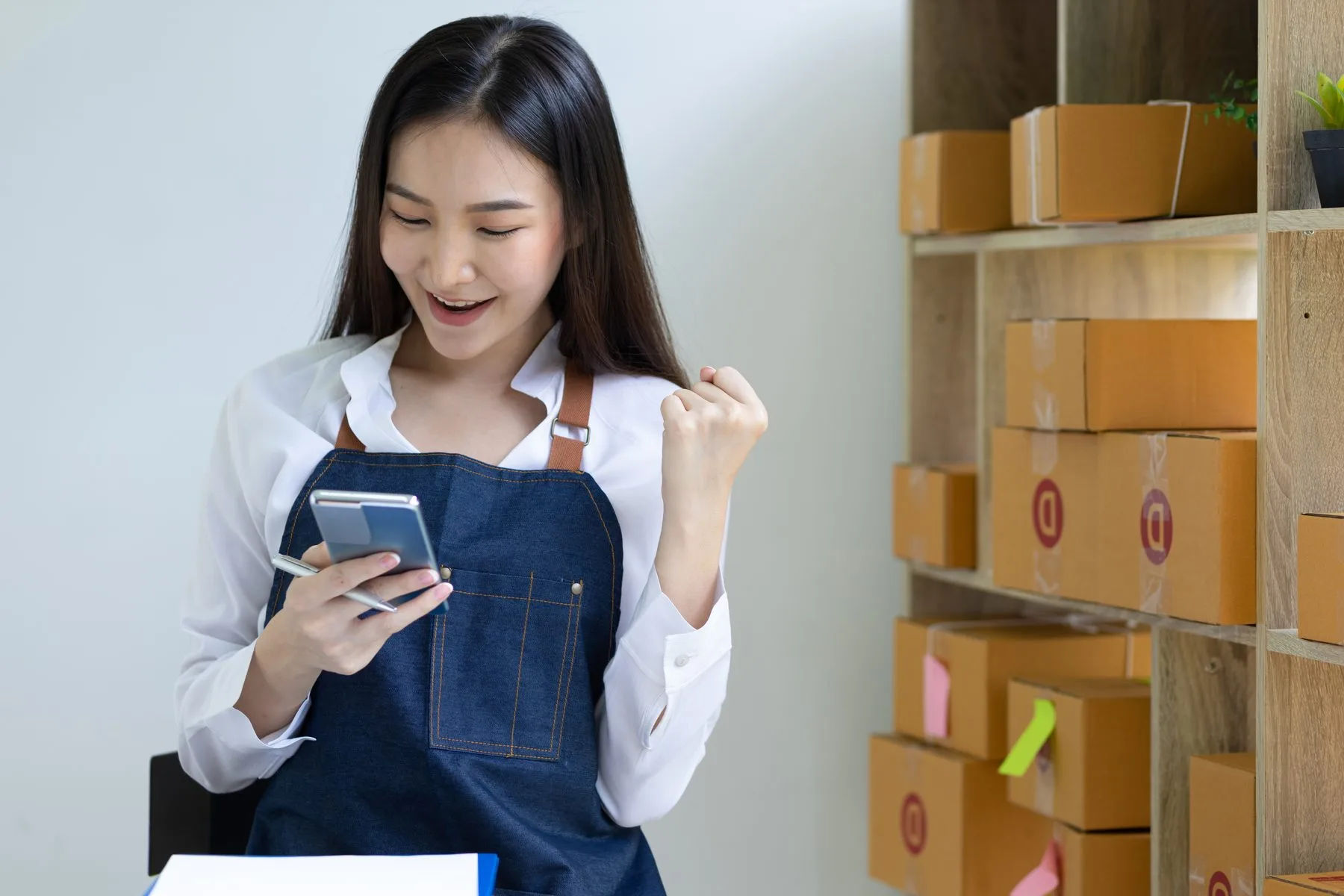 Woman with phone celebrates business success in wo