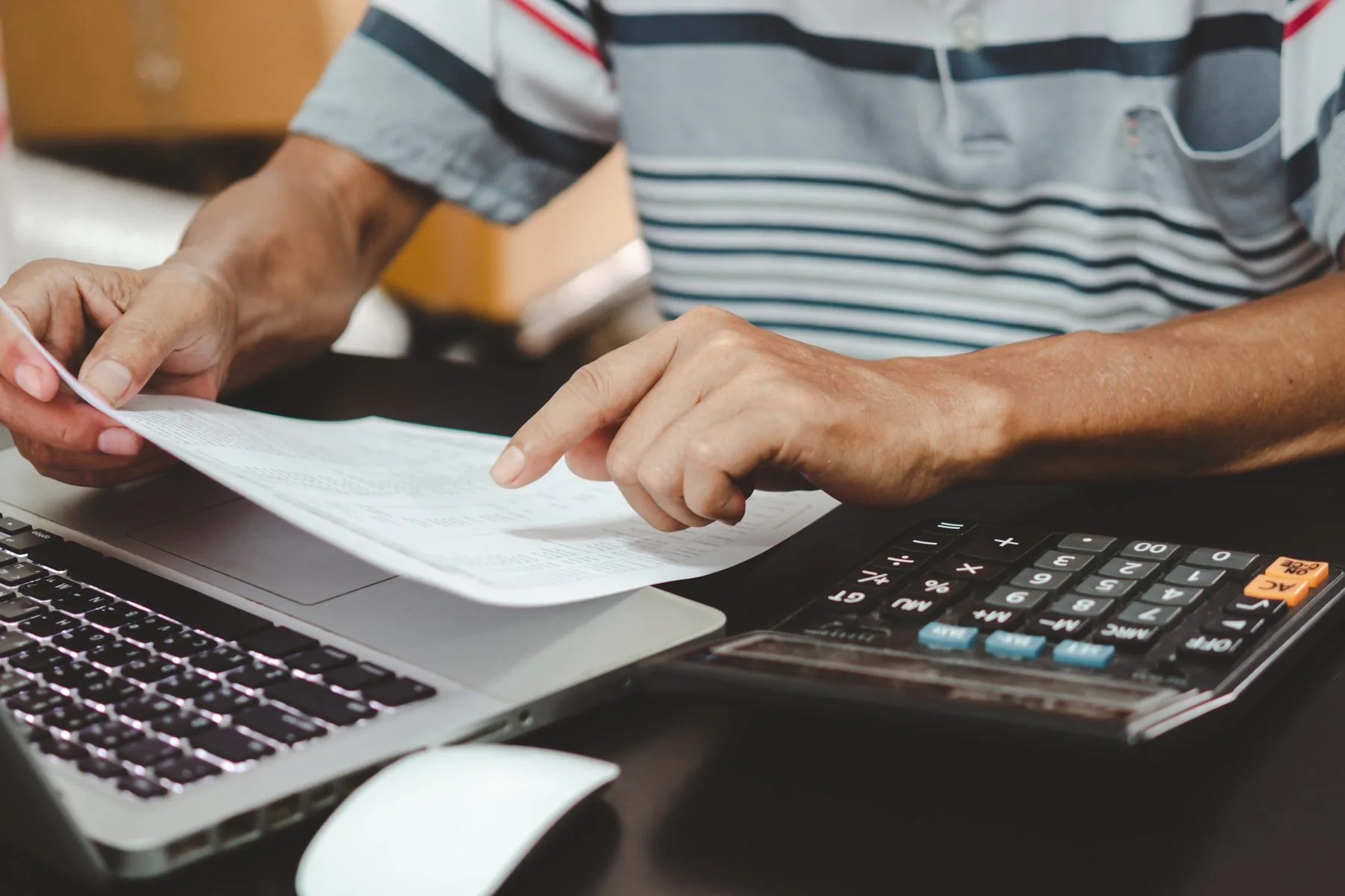 Senior looks over figures with laptop and calculat