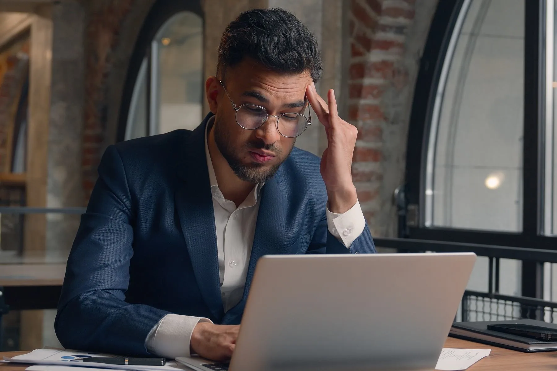 Man working at desk with laptop looking stressed