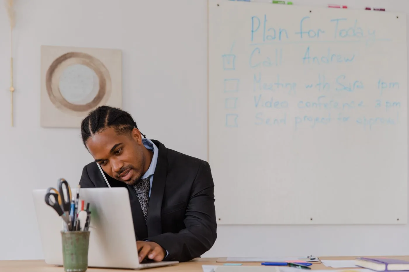 Businessman at his desk in an office working on a laptop and making phone calls