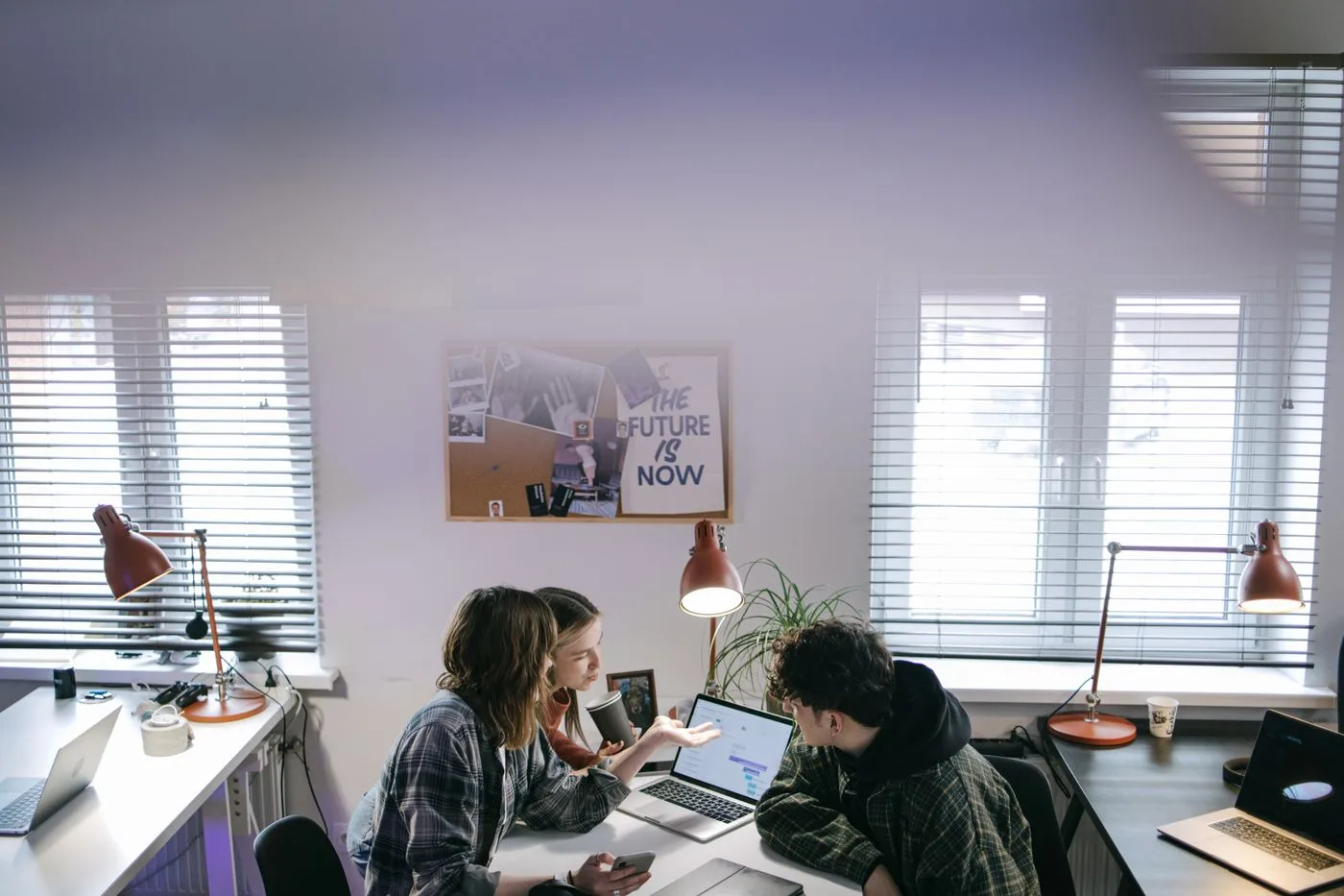 A group of people discussing ideas around laptops in a bright, modern office space