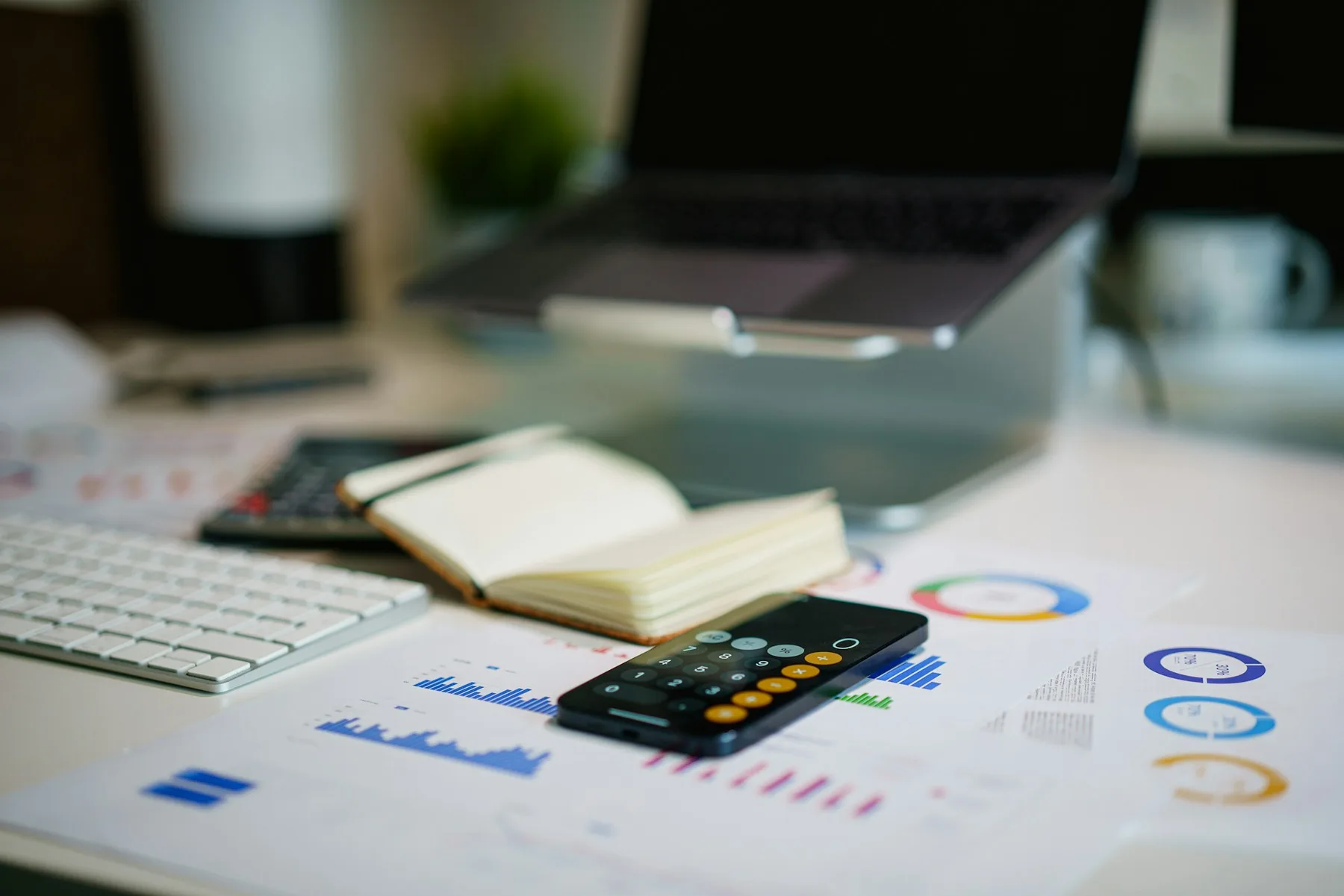 Desk with printed marketing reports, charts and a calculator, illustrating how to plan an online marketing budget.
