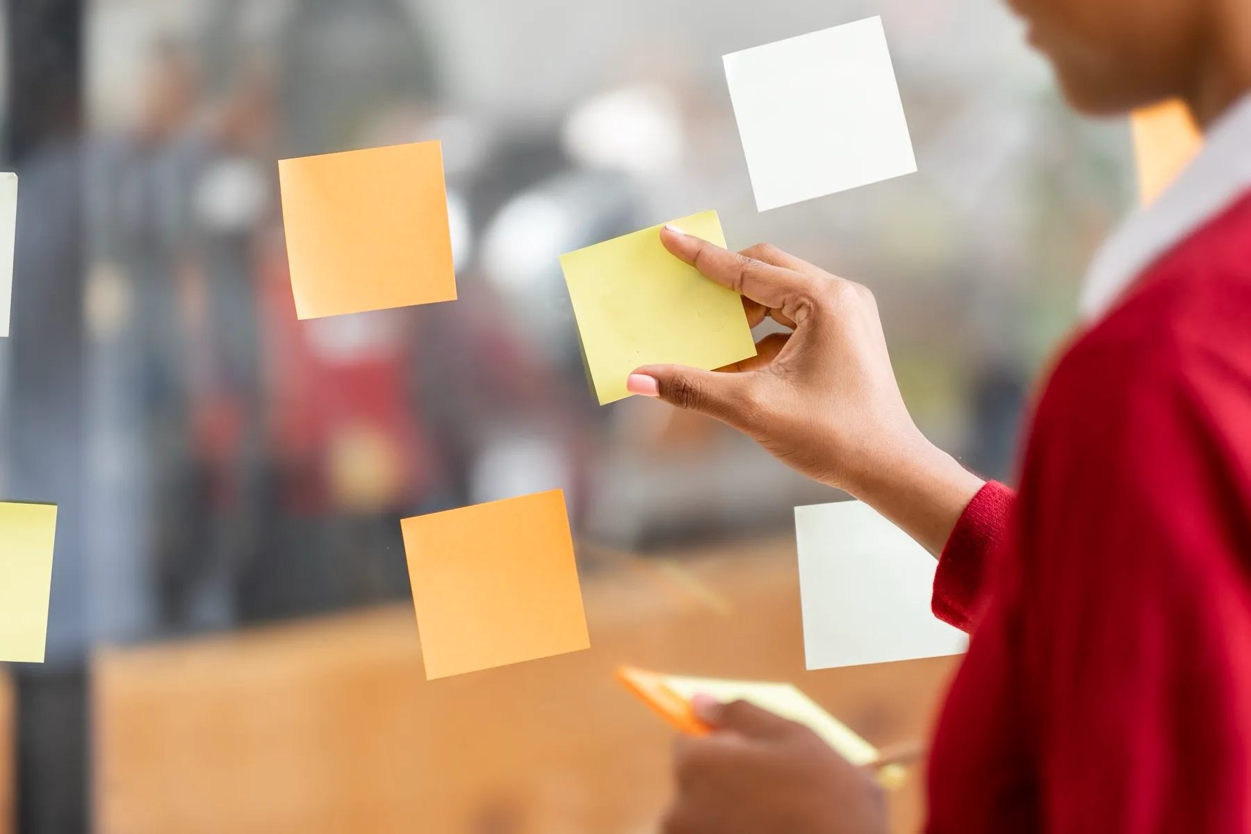 Woman arranging sticky notes on a glass wall while planning