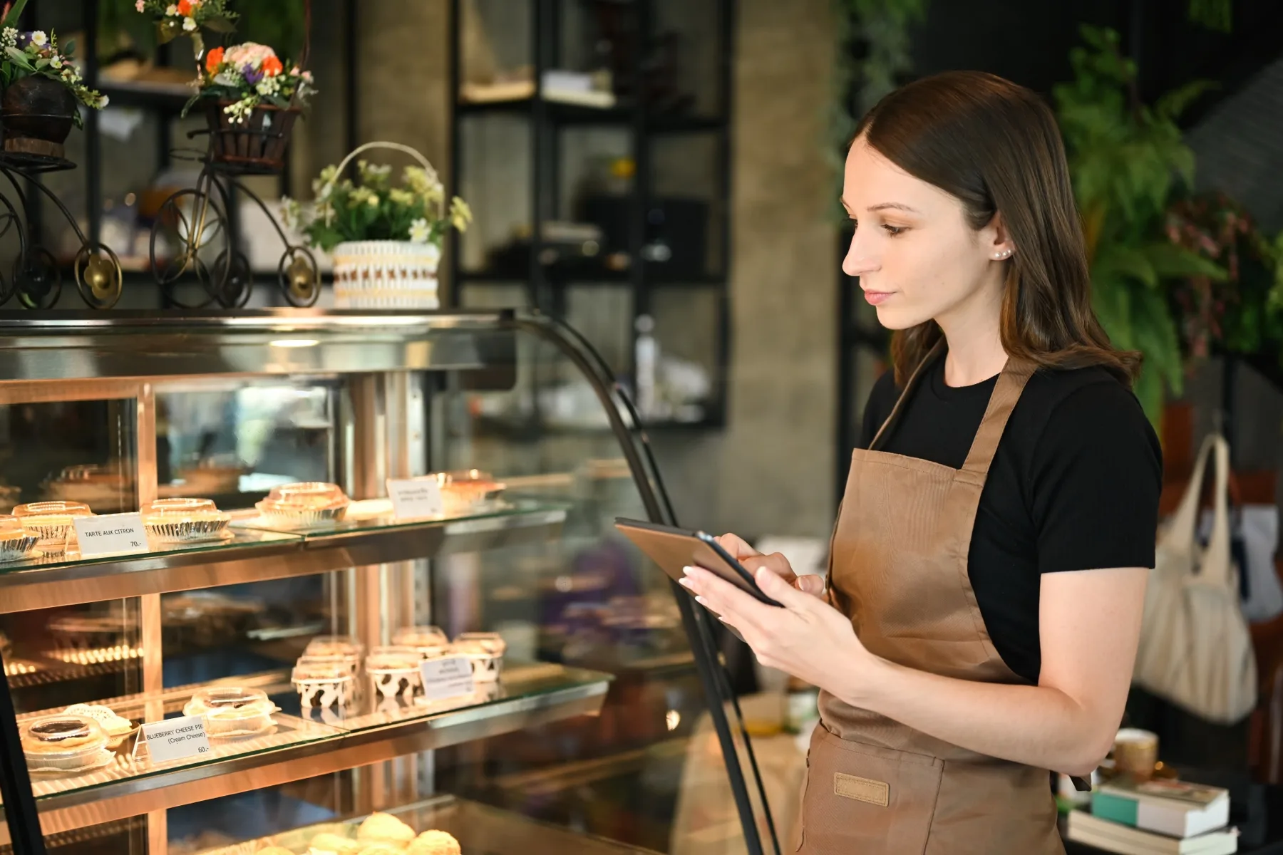 Woman in an apron using a tablet in a bakery