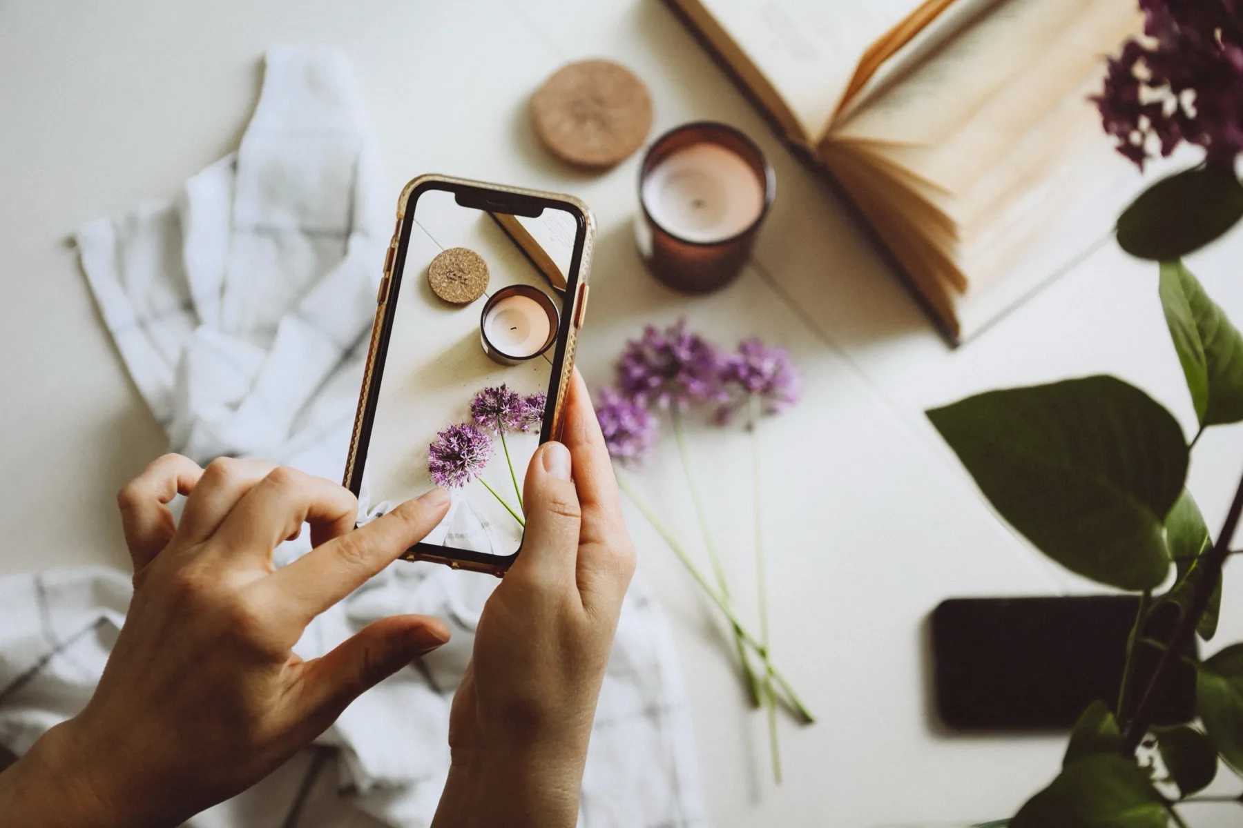Hand photographing a styled still life with a smartphone