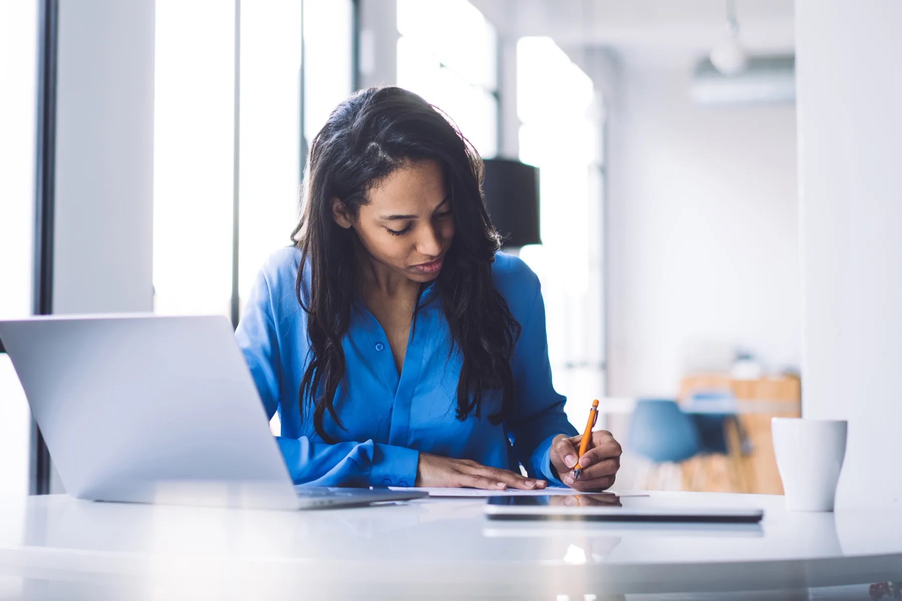 Professional working at a laptop and writing notes in a bright office