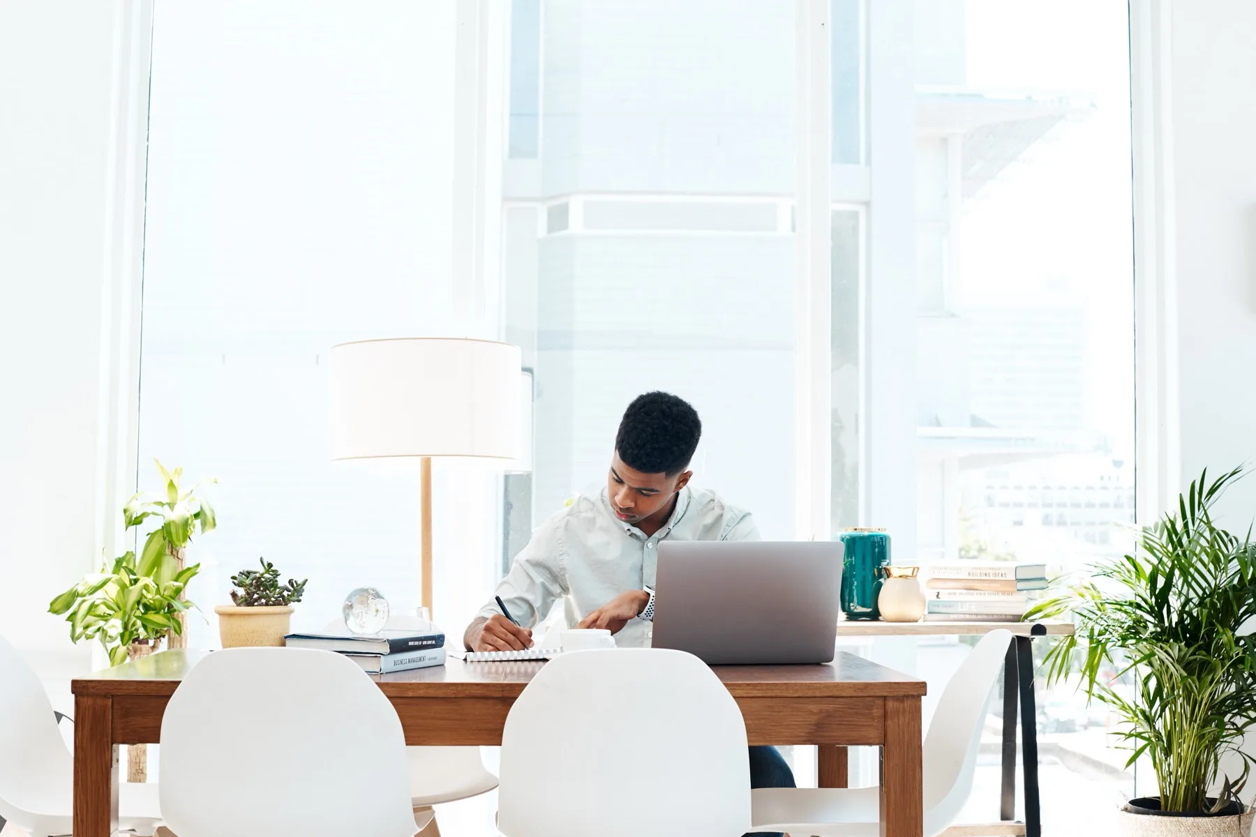 Man working at a laptop in a bright office with plants
