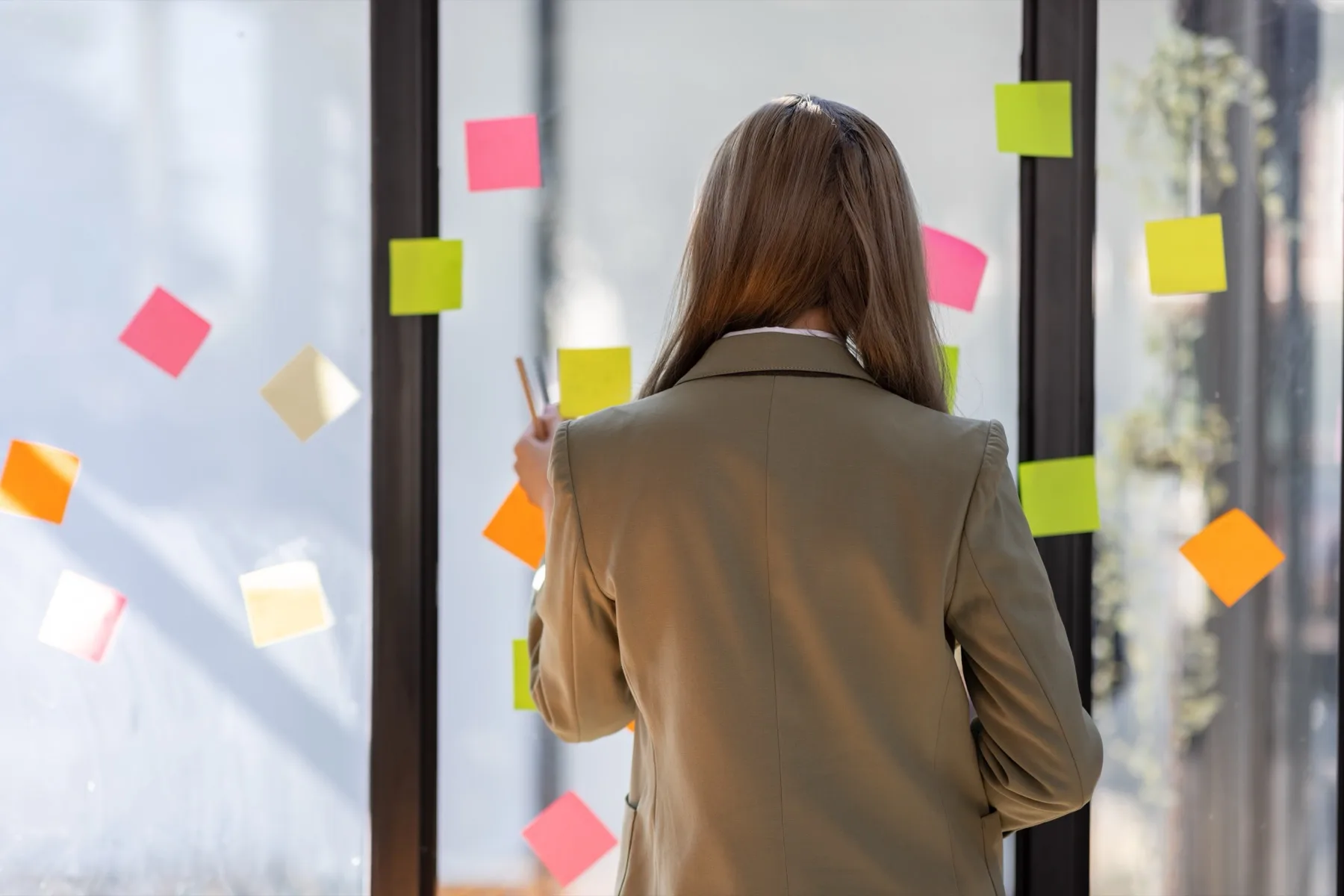 Woman planning ideas on sticky notes on a glass wall