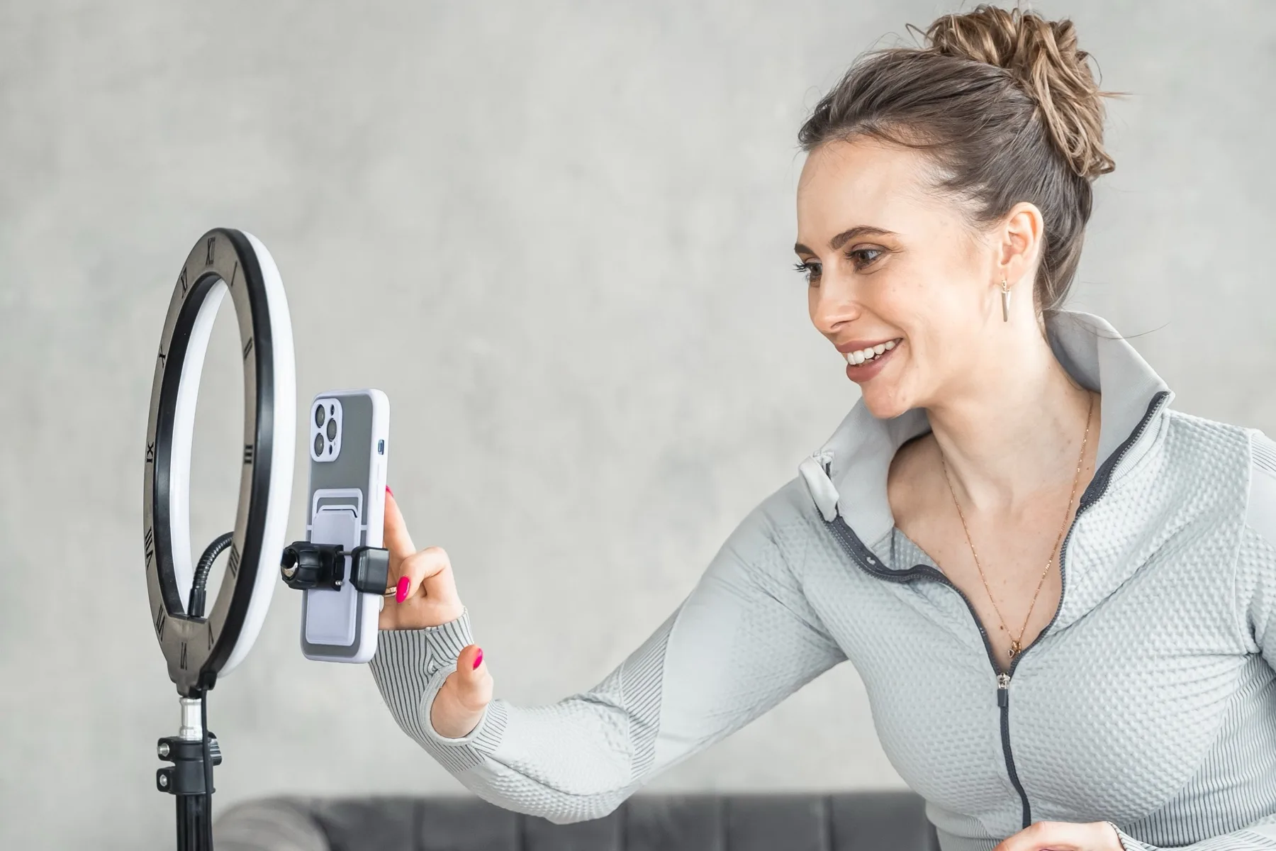 Woman filming herself on a smartphone mounted in a ring light