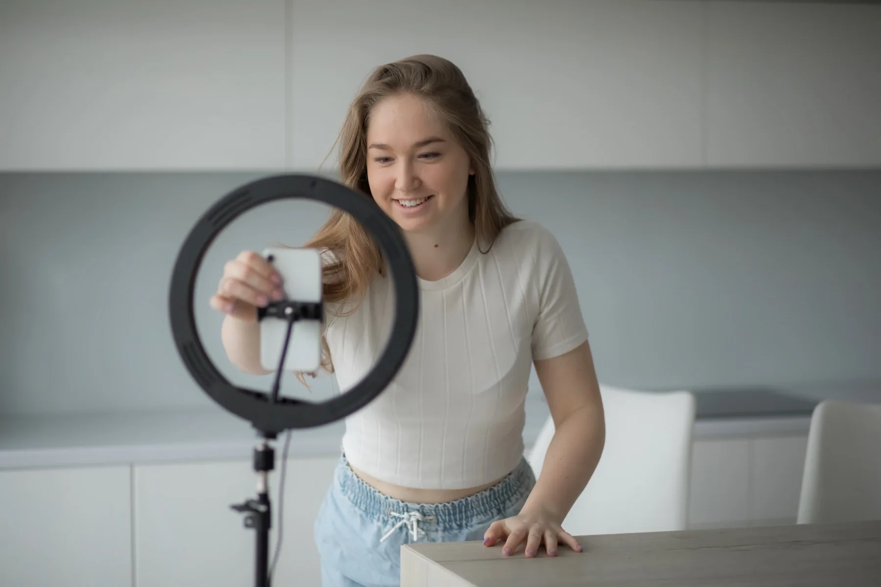 Young woman recording a video at home with her phone in a ring light