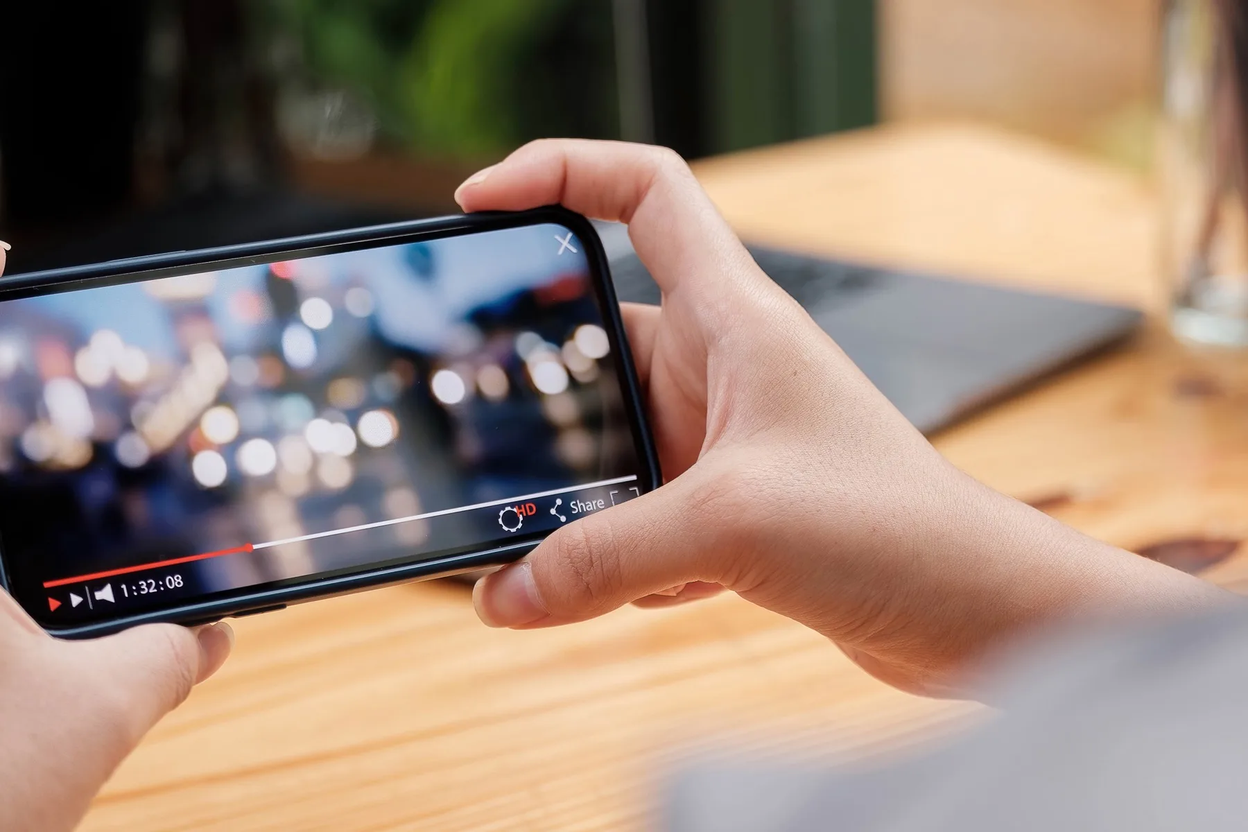 Hands holding a smartphone sideways to watch a video