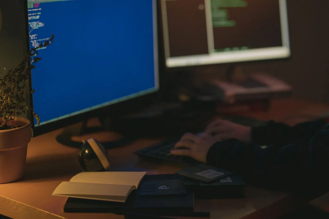 Individual programming in a dimly lit room with dual monitors