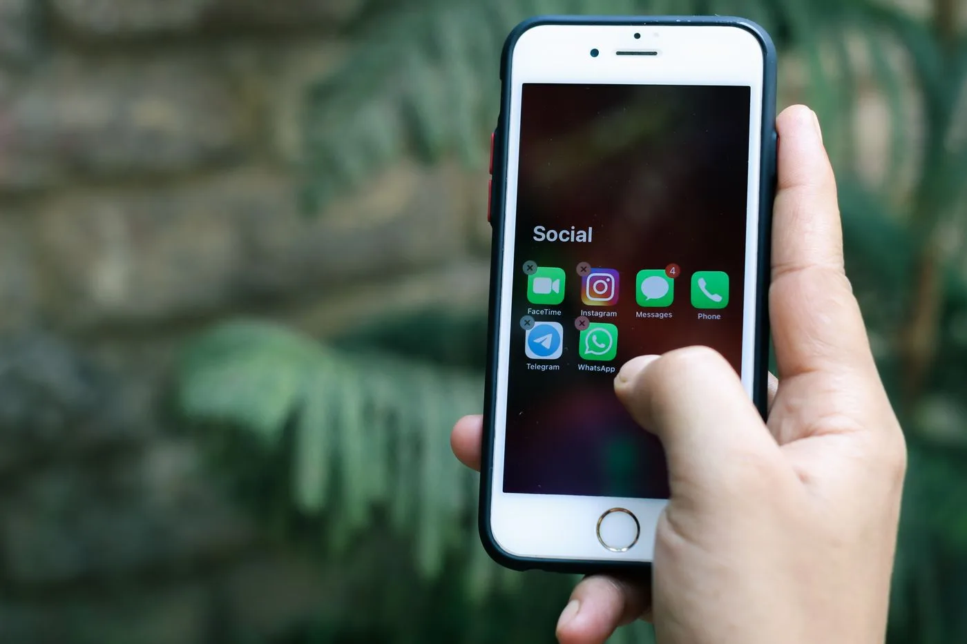 Close-up of a hand holding a smartphone displaying social media apps outdoors